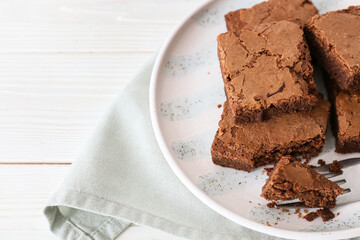 Plate with pieces of tasty chocolate brownie on white wooden background, closeup