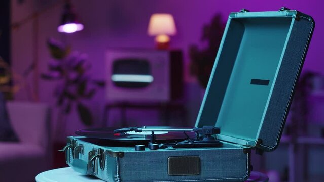 Vinyl record close-up. Vintage old vinil black phonograph spinning. Retro music player on living room home background in evening, pink neon light.