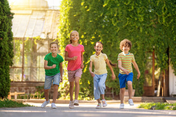 Naklejka na ściany i meble Children running in park on sunny day