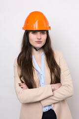 A girl architect in a suit and an orange construction helmet stands on a white background.