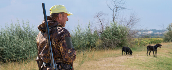 Hunter man in camouflage with a gun during the hunt in search of wild birds or game. Autumn hunting...