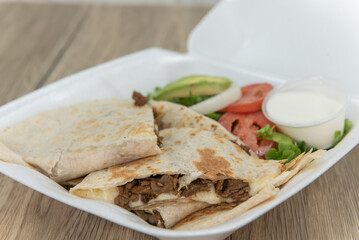Take out order of carne asada tortilla quesadillas cut into triangle pieces and served in styrofoam box