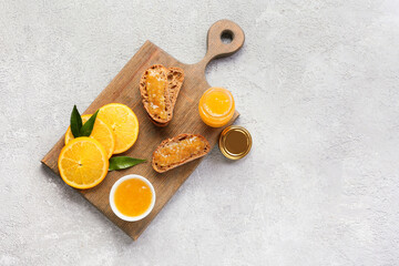 Tasty orange jam and bread on light background
