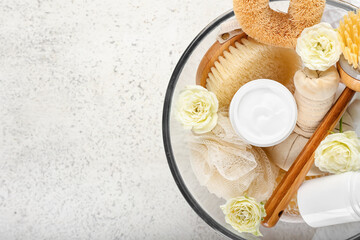 Bowl with natural cosmetic cream, brush and flowers on light background