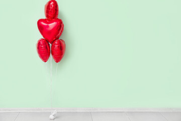 Beautiful heart-shaped balloons for Valentine's Day celebration near color wall in room
