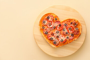 Wooden board with tasty heart-shaped pizza on beige background. Valentine's Day celebration
