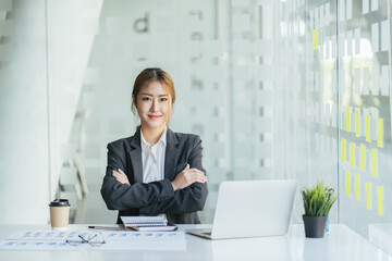 Cheerful smiling business woman working with laptop computer while sitting at the desk in modern office.