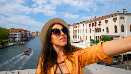 Travel influencers Venice island. Paint building house in Europe Venezia city. Photographer blogger girl with smartphone in Venice San Marco square. Traveling and freelancing, modern lifestyle.