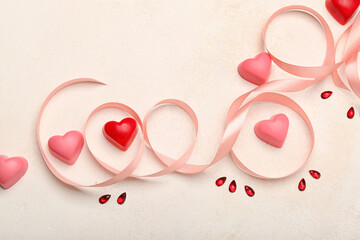 Different chocolate candies in shape of heart and ribbon on light background. Valentine's Day celebration