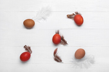 Brown Easter eggs and feathers on white wooden background