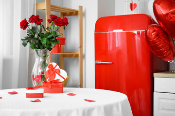 Gift boxes and vase with roses for Valentine's Day celebration on dining table in light kitchen