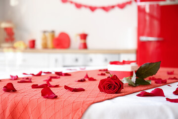 Rose, petals and gift box on dining table in kitchen decorated for Valentine's Day celebration