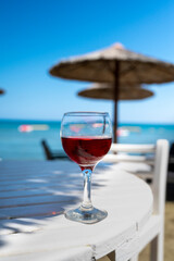 Drinking of cold rose wine in lounge bar on sunny sandy beach with blue sea water on background