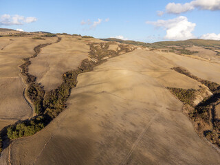 Fototapeta na wymiar Aerial panoramic view on hills of Val d'Orcia near Pienza, Tuscany, Italy. Tuscan landscape with cypress trees, vineyards, forests and ploughed fields in autumn.
