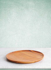 Empty round wooden plate on white cement table and green cement wall background, Blank wood tray...