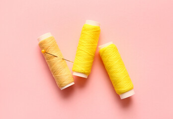 Yellow thread spools with ball pin on color background