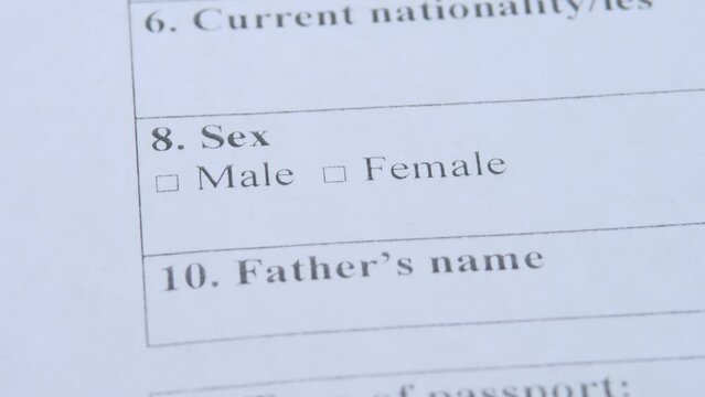 Unrecognizable man's hand by pen vote checkbox in paper blank. Male status in application form. Concept of sexism, prejudice or discrimination based on one's sex or gender