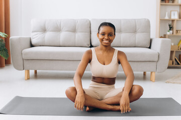 Fototapeta na wymiar Young black woman meditating at home, yoga online concept, free space