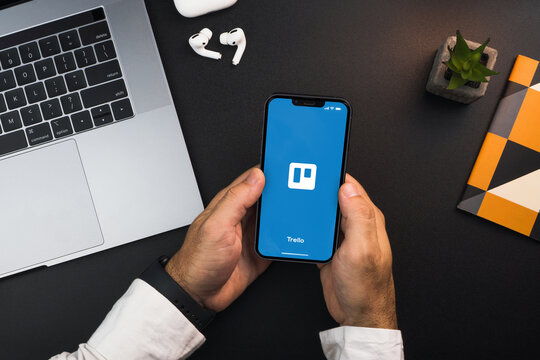 Man holding a smartphone with Trello app on the screen on black background table. Office environment. Rio de Janeiro, RJ, Brazil. February 2022