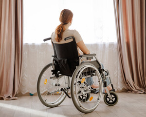 Caucasian woman in a wheelchair at the window. 