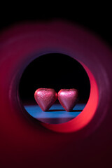 Concept of heart-shaped chocolate confections at the end of an illuminated tunnel.