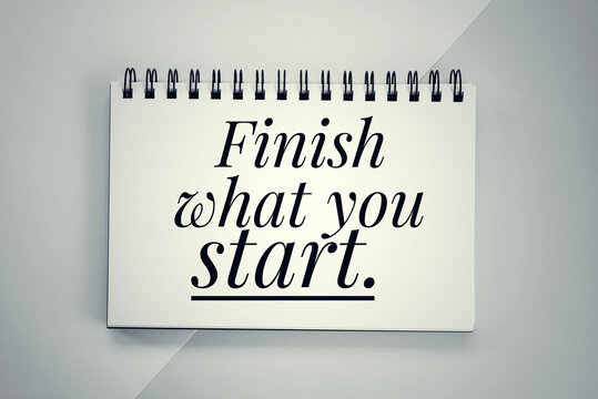 Motivational words - Finish what you start. Text message on a spiral notebook. Inspirational quote concept on paper book.