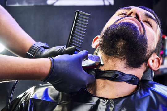 Fototapeta detalle de la mano de un barbero cortando delicadamente la barba de uno de sus clientes