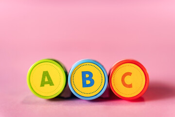 Word ABC in letters text from kid's toy stamps isolated on a pink background, learning alphabet for toddlers