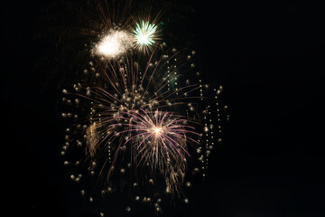 Bright fiery rays from exploding pyrotechnics against the black background of the night sky. Background with festive fireworks.