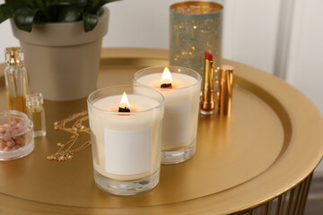 Fototapeta na wymiar Burning soy candles, cosmetics and stylish accessories on table indoors