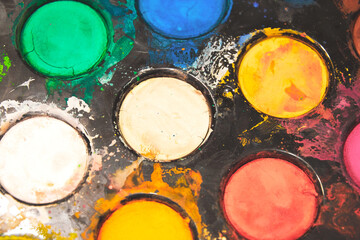 Round palette of the kid painter with dry watercolor paints. Hobby and leisure activities backgrounds