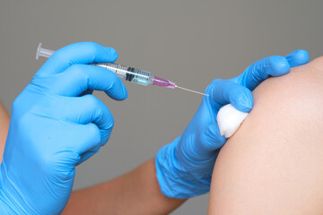 doctor's hand holds a syringe and a blue vaccine bottle at the hospital. Health and medical concepts.