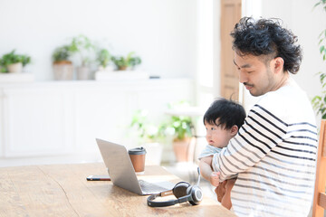 Baby being held in a baby carrier while Dad is at work and participating in Zoom. Copy space available.