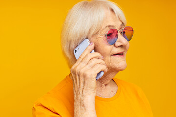 Photo of retired old lady in fashionable glasses with a smartphone isolated background