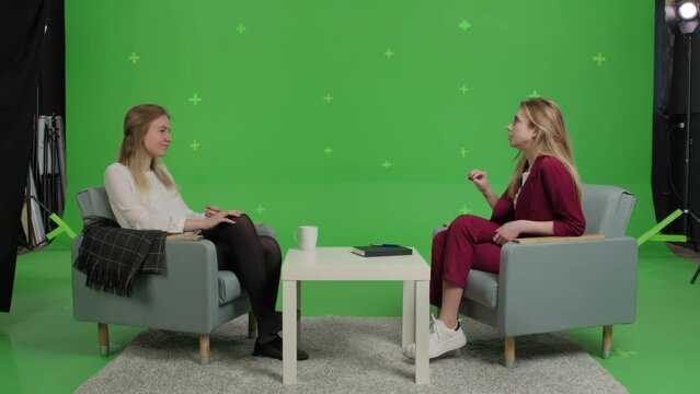Young female patient and woman psychologist at psychotherapy session over green screen background. Youth talk show interview with a famous guest