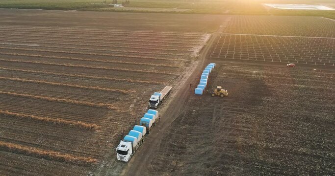 Kibbutz, Israel - 25 November 2021: Aerial view of a tractor loading cotton bales on truck, Kibbutz Saar, Mate Asher, Israel.