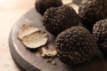 Obraz na płótnie Canvas Whole and cut black truffles with wooden board on table, closeup