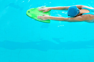 
young woman in a blue swimsuit swims in the pool