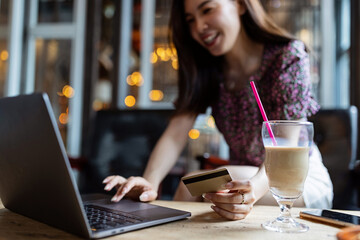 Pretty young asian business woman using laptop in modern cafe. 
