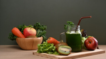Fresh homemade green smoothie and organic vegetables on a wooden table.