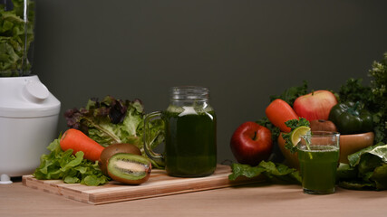 Green smoothie with fresh vegetables and blended on wooden table.