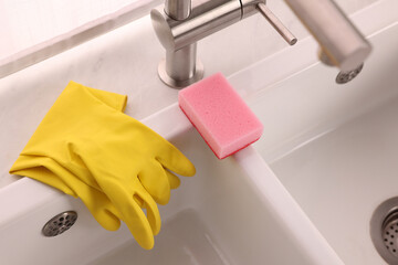 Sponge and rubber gloves on kitchen sink indoors, above view