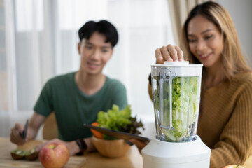 Healthy young couple enjoy making green vegetables smoothie with blender in kitchen.