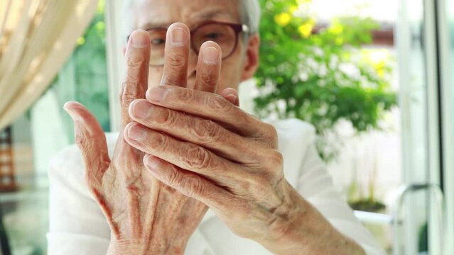 Elderly woman massaging her wrist,palm and finger,painful in hands,old senior suffer from gout,rheumatoid,chronic arthritis with pain,injury wrist bones,beriberi in hand or numbness of the fingertip