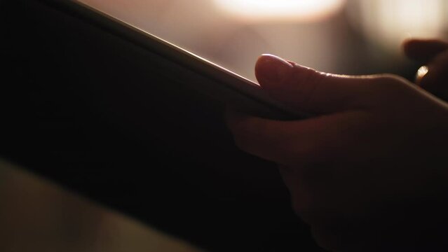 Women's hands hold the tablet and press the screen.