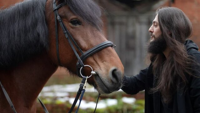 horse rider is communicating with his horse, handsome and enigmatic man