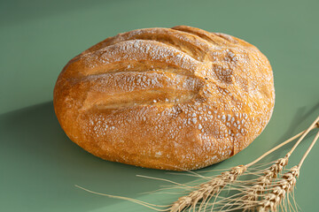 Freshly baked loaf of creamy bread on green background