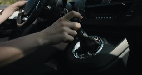 Female hand shift gear gearshift lever drive car sunny light close up