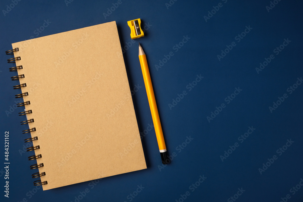 Poster top view brown notebook with yellow pencil and notepad on navy blue working table
