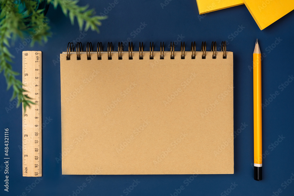 Poster top view brown notebook with yellow pencil and notepad on navy blue working table